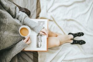 garota segurando um livro e uma xícara de café em um momento de autocuidado