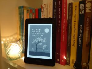 Livro de Haemin Sunim, A coisas que você só vê quando desacelera, em formato de Kindle em uma estante com outros livros atrás. Há uma vela do lado esquerdo.